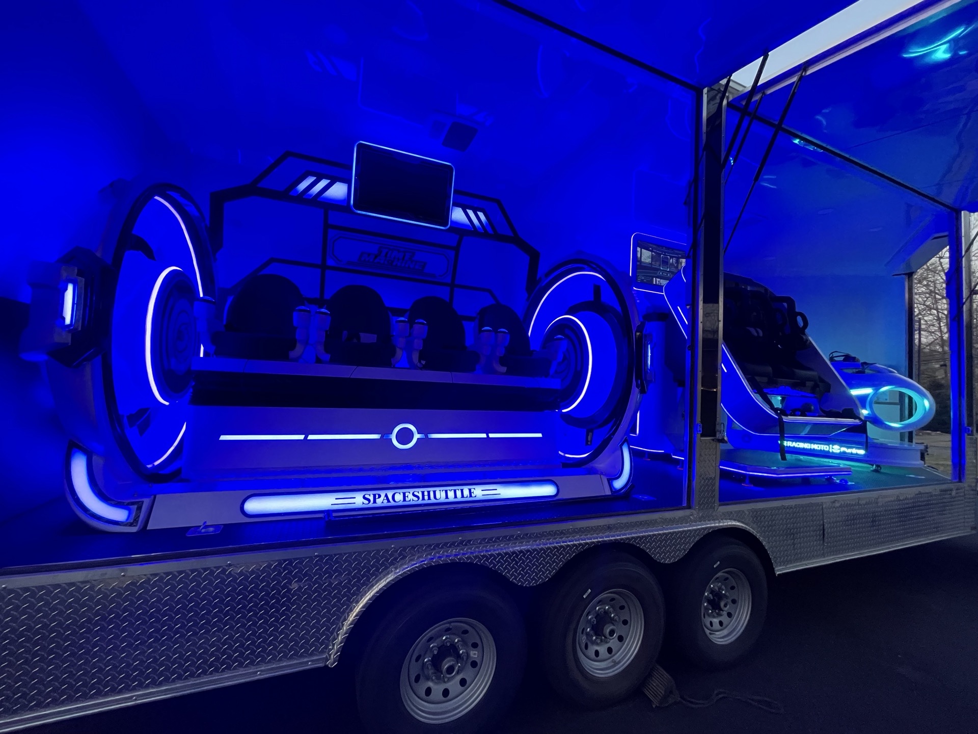 Exterior side of VIP Virtual Thrills trailer with Space Shuttle logo and blue neon lighting