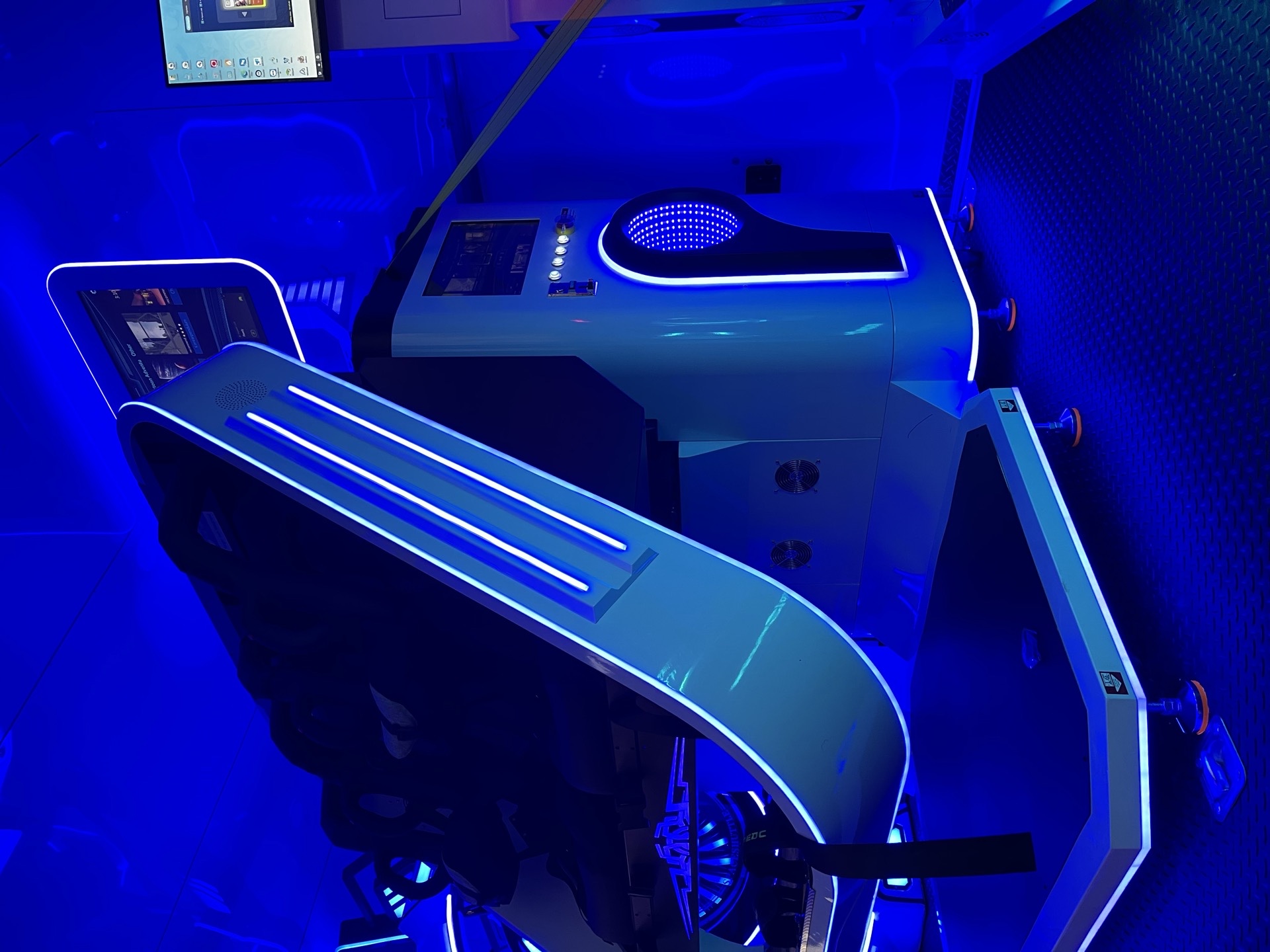 VR motion seat roller coaster rig with curved frame and blue neon lighting inside the trailer